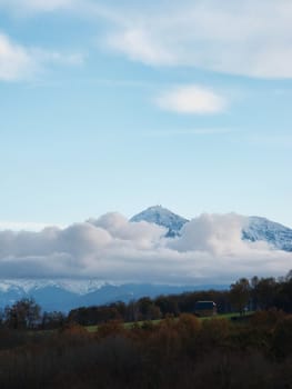 Pyrenees mountains range in clouds with field in the foreground