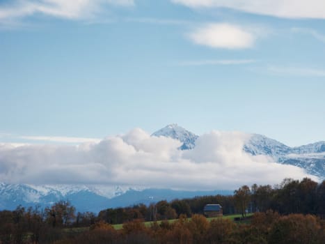 Pyrenees mountains range in clouds with field in the foreground