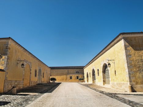 Big yellow house with an empty  alley in France under pure blue sky
