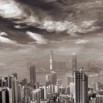 Hong Kong skyline with dramatic clouds and skyscrapers in sepia tone.