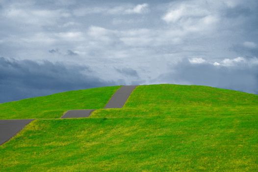 colorful grassland in summer under cloudy sky with path up the hill