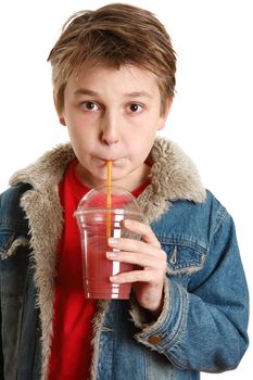 A young boy drinking fresh mixed berry health juice in a clear cup container with a yellow straw.  He is wearing a red t-shirt and a blue denim jacket.