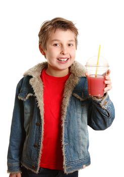 A happy young boy holding a freshly made juice in a clear disposable cup.   He is smiling cheerfully.