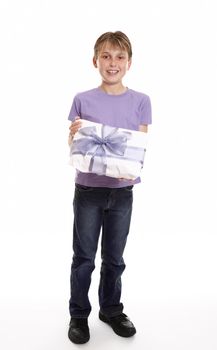 A boy smiles with a wrapped present tied up with big ribbon bow