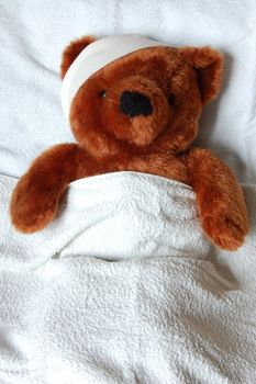 sick teddy bear with injury in a bed in the hospital