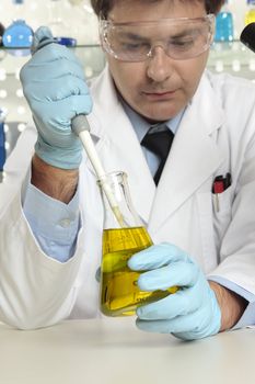 Scientist, chemist or pharmacist using a pipette and erlenmeyer flask in a laboratory.  Focus to pipette and flask.