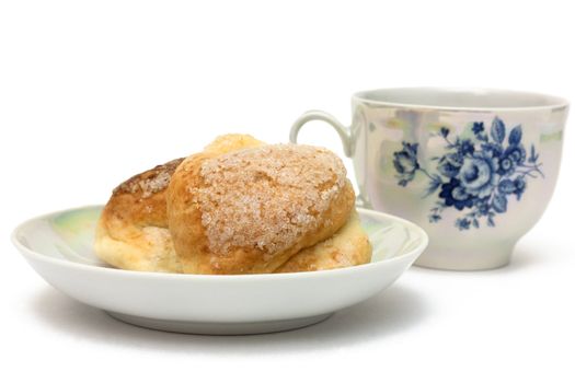 Baked goods on a saucer with a cup of tea isolated on white