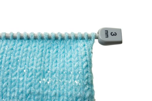 Woollen texture and knitting needle isolated on white