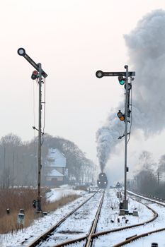 Old retro steam train starting from the station during wintertime
