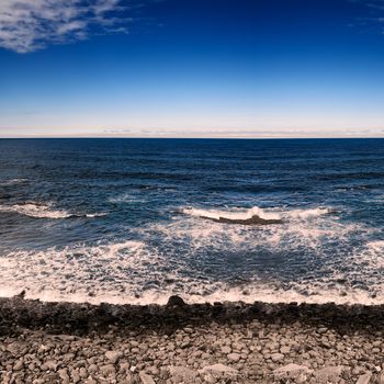 Coastline and the sea with rock and wave under the blue sky.
