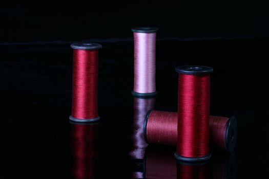 Colour threads of different colours for sewing on industrial coils, the picture is made by hectare a black reflecting background.