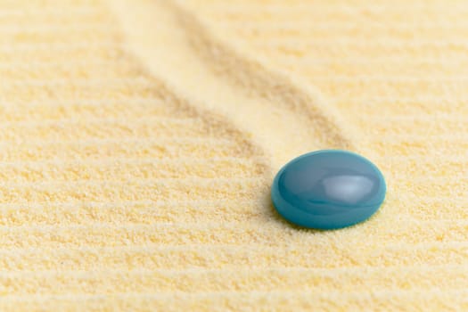Abstract composition - a sandy wavy yellow surface and a blue glass drop