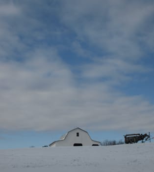 A white barn on a hill during the winter months