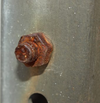 A rusted metal nut and bold holding up a metal post