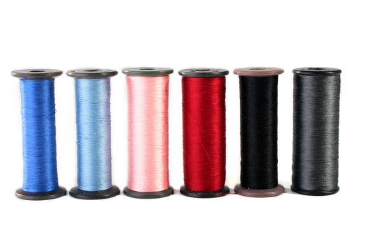 Colour threads for an embroidery on a white background. Threads on coils for industrial use.