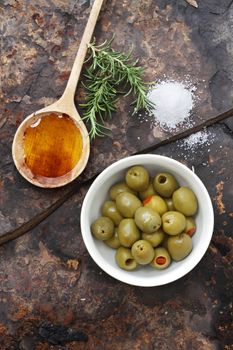 Spanish olives with olive oil, rosemary, sea salt and olive on a rustic slate background. 