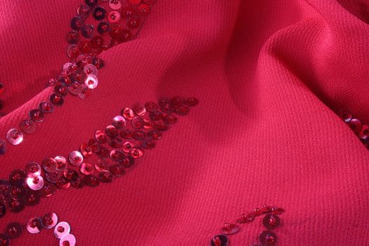 Darkly red fabric with an embroidery from seed bead for use as a background.