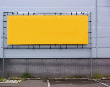Empty yellow billboard against a factory wall