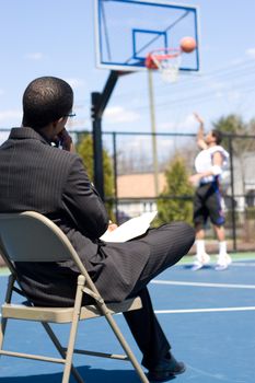 A basketball coach or scout recruiter observes an athlete while he warms up.