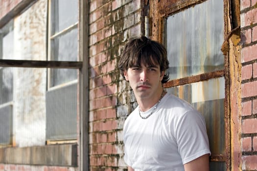 A confident young model standing in a grungy urban setting.