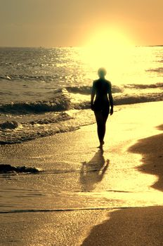 Sundown on sea and girl alone on the beach