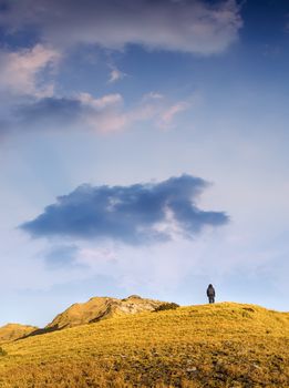 Dramatic landscape of lonely man walking toward mountain.