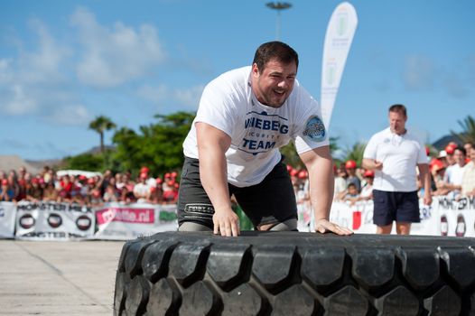 CANARY ISLANDS - SEPTEMBER 03: Jimmy Laureys (l) from Beligium lifting and rolling a wheel (weights 400kg) 8 times during Strongman Champions League in Las Palmas September 03, 2011 in Canary Islands, Spain