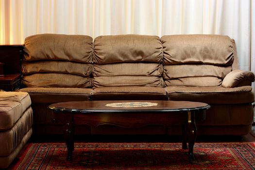 Interior of a room with an angular sofa and a coffee table.