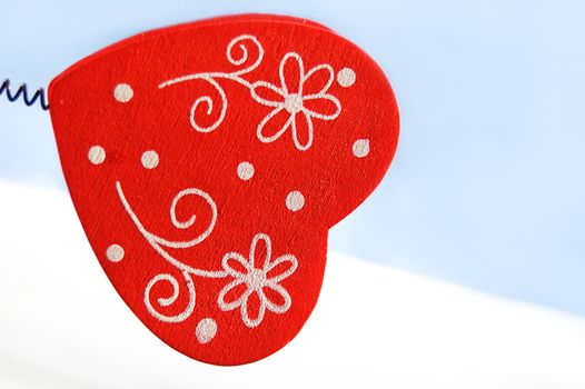 Red wooden heart over white and blue background