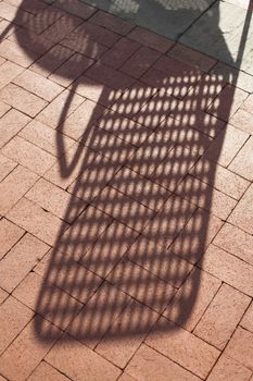 Closeup of Red Brick Sidewalk With a Shadow of a Chair and Table