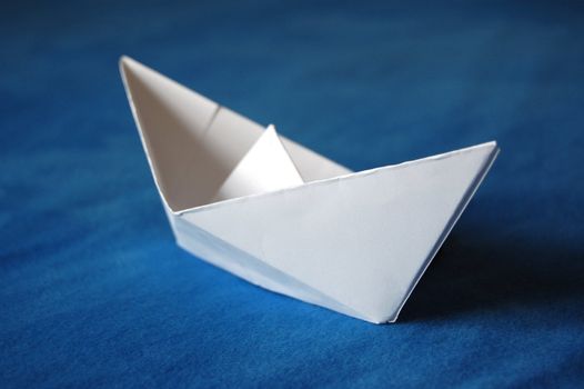 origami paper boat isolated on blue water