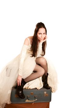 Woman in a wedding dress sitting on suitcases