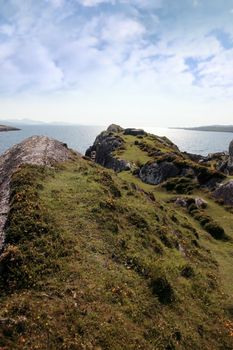 scenic view in kerry ireland of rocks and sea with mountains against a beautiful bright sunny sky