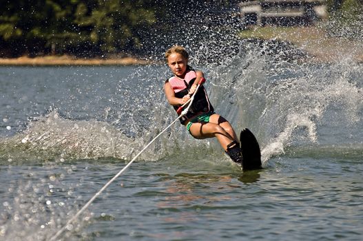 A young girl waterskiing on a slalom course.