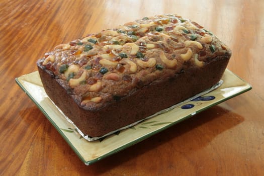 banana bread loaf topped with glazed fruit and nuts 
