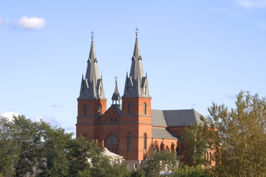 A red church stands against a cloudy blue sky.