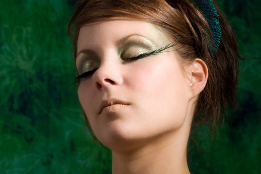 Beautiful woman with eyelashes made out of peacock feathers