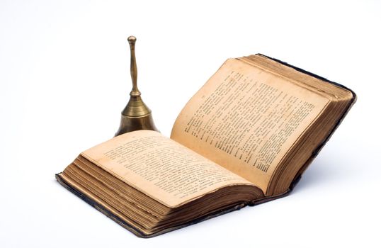 Old book and handbell over white