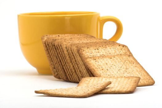A stack of crackers and yellow cup over white