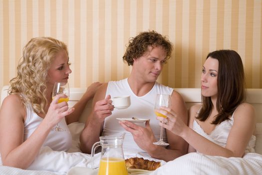 Threesome having a breakfast in bed