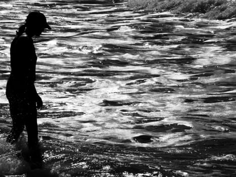 Silhouette of athletic woman watching glistening waves of the ocean