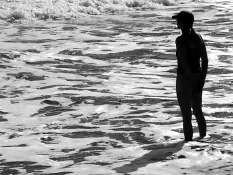 Silhouette of athletic woman watching glistening waves of the ocean