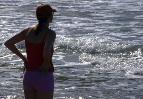 Silhouette of athletic woman watching glistening waves of the ocean