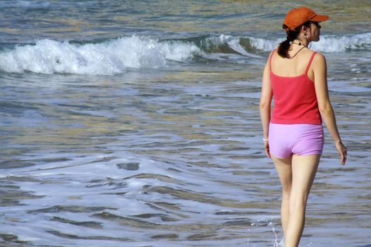 Woman brisk-walking along beach in the Mediterranean