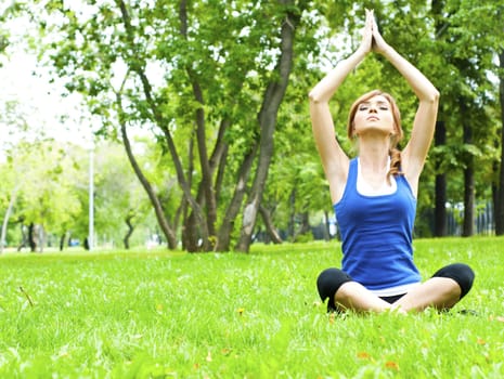 young woman is engaged in yoga, in summer on a green grass