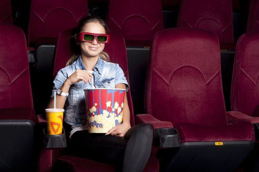 young woman sitting alone in the cinema and watching a movie