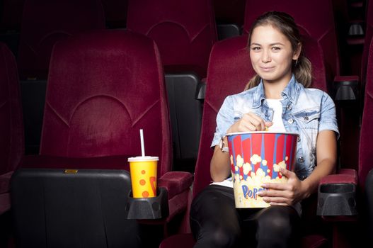 young woman sitting alone in the cinema and watching a movie