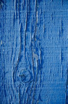 Blue flaky paint on a wood background.