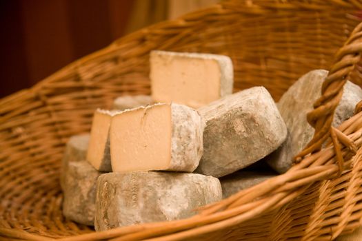 Cheeses in a cane basket on a market stall. Shallow DOF.