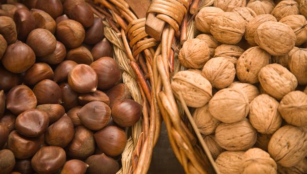 Hazelnuts and walnuts in baskets on a market stall. Shallow focus.